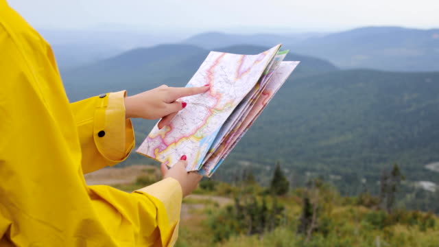 Young-female-Hiker-looking-at-map-from-mountain-top
