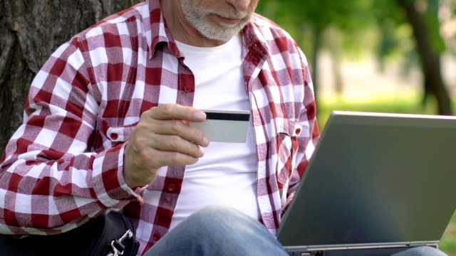 Old-man-paying-for-utilities-with-credit-card,-using-laptop,-money-transaction