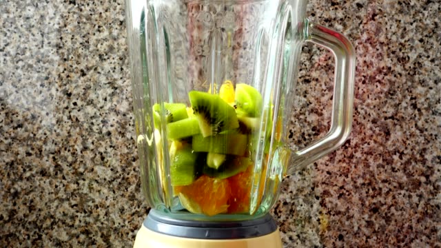 Filling-in-the-blender-of-a-kiwi,-oranges-and-bananas.	Preparation-of-smoothie-in-the-blender.