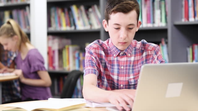 Männlichen-High-School-Schüler-arbeiten-am-Laptop-In-der-Bibliothek