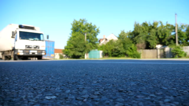 Truck-is-driving-along-an-asphalt-road.-Blurred-car-is-riding-at-the-highway-at-the-sunny-summer-day.-Low-angle-view-Close-up-Slow-motion