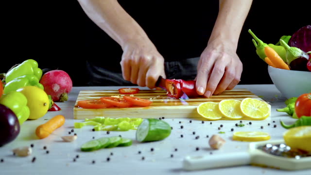 Man-is-cutting-vegetables-in-the-kitchen,-slicing-red-bell-pepper