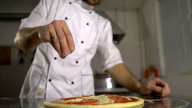 El-chef-rocía-especias-a-la-pizza-acabada-en-la-cocina