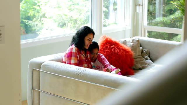 Mother-and-daughter-reading-book-in-living-room-4k