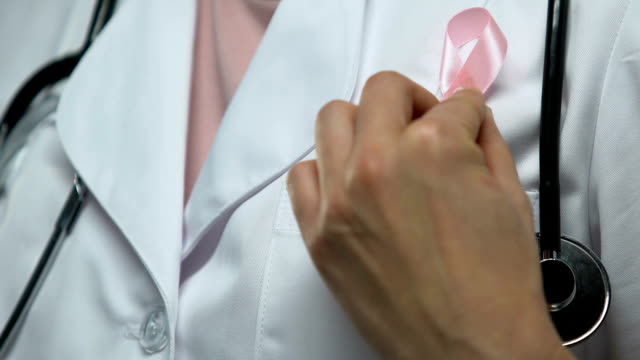Doctor-pins-up-pink-ribbon,-global-fight-against-breast-cancer,-healthcare