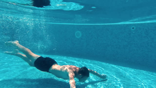 Junger-Mann-schwimmt-unter-Wasser-in-einem-Schwimmbad