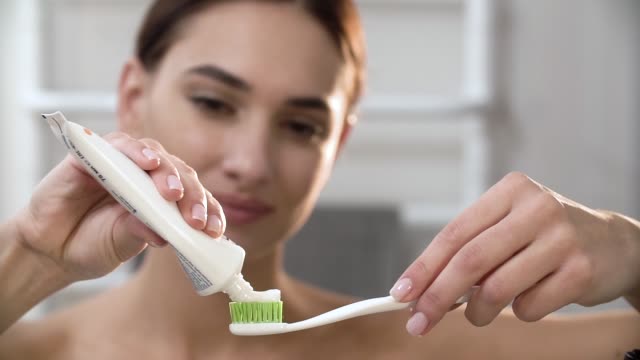 Zähne-Hygiene.-Frau-Anwendung-Zahnpasta-auf-die-Zahnbürste-Closeup