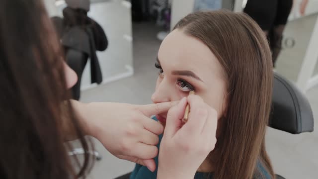 Professionelle-Make-up-Künstler-Frau-malt-Wimpern-an-Kunden-des-Schönheitssalons