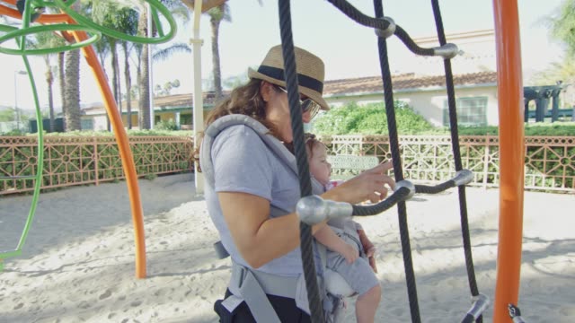 Woman-with-a-baby-in-carrier-at-a-playground