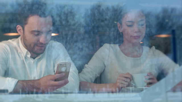 Mujer-se-aburra-en-la-cafetería-mientras-su-novio-está-ocupado-con-el-teléfono