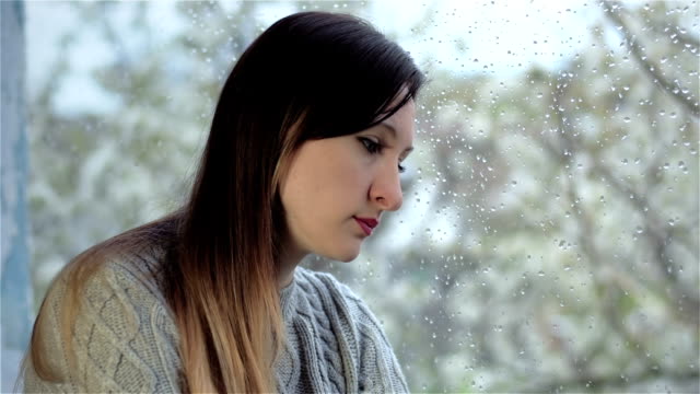 Sad-woman-leaned-her-cheek-against-wet-window.-Close-up