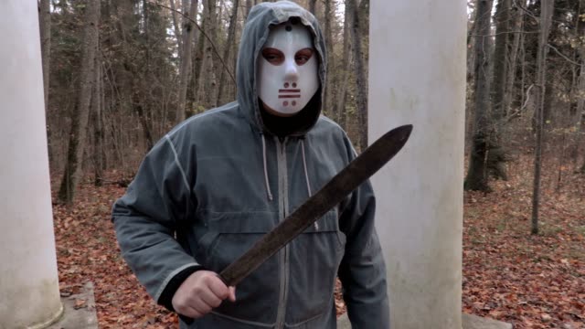 Camera-is-approaching-man-in-scary-Halloween-mask-and-machete