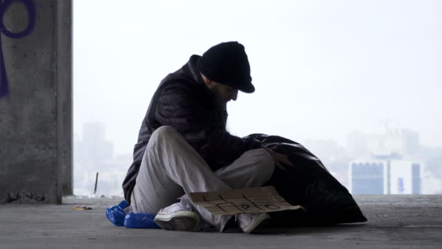 Hombre-sin-hogar-que-se-va-a-dormir-en-la-bolsa-de-basura,-fondo-urbano