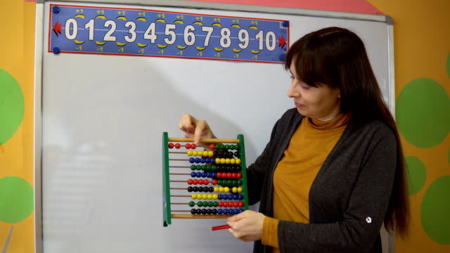 Female-teacher-stand-near-blackboard-in-elementary-school-teaching.