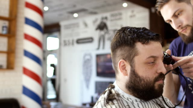 Hairdresser-makes-hairstyle-to-a-young-bearded-man