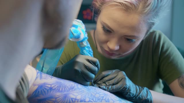 mujer,-un-artista-del-tatuaje,-hace-un-tatuaje-en-el-salón.