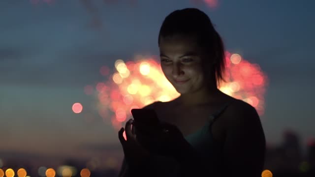 Eine-Mädchen-nutzt-eine-Smartphone-während-ein-Feuerwerk
