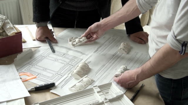 Hands-of-male-sculprot-and-architector-comparing-white-plaster