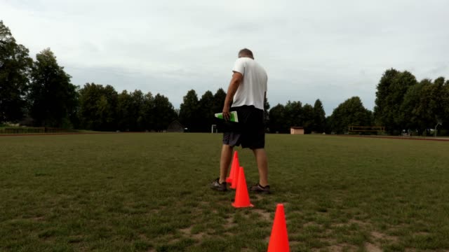 Entrenador-coloca-conos-rojos-en-el-campo-de-fútbol