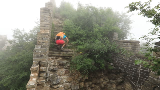 Woman-hiker-climbing-up-to-the-top-of-unrestored-great-wall
