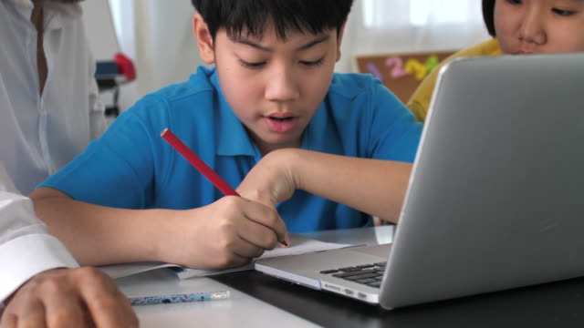 Tutor-room-children-in-class-learning-on-laptop-computer-with-teacher.-4K-Slow-motion-Asian-child-learning-with-teacher-at-home.