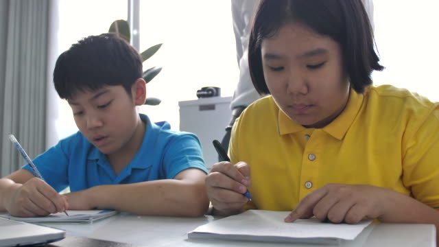 Tutor-room-children-in-class-writing-on-board-with-teacher.-4K-Slow-motion-Asian-child-learning-with-teacher-at-home.