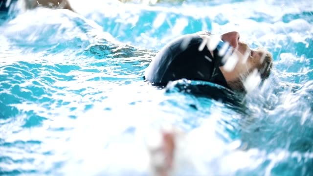Behinderte-Mensch-schwimmt-auf-der-Rückseite-in-einem-Schwimmbad.-Slow-Motion.-Seitenwinkel