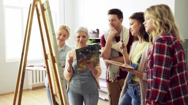 group-of-artists-discussing-painting-at-art-school
