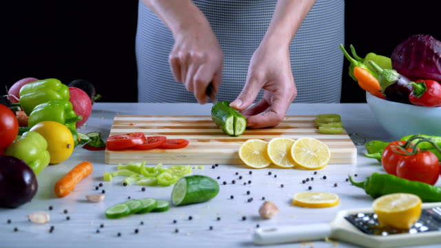 Man-is-cutting-vegetables-in-the-kitchen,-slicing-cucumber
