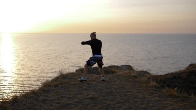 self-defense-training,-boxer-male-practicing-fist-fight-before-competition-on-hill-near-sea