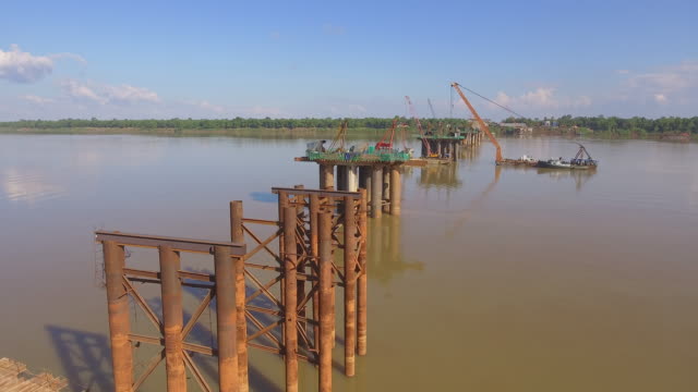 drone-shot:-fly-over-columns-of-new-bridge-under-construction-in-river