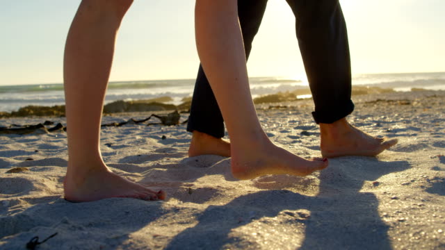 Low-section-of-couple-walking-at-beach-on-a-sunny-day-4k