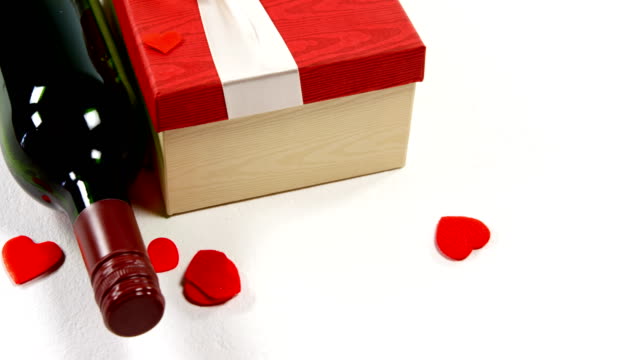 Wine-bottle,-gift-box-and-red-heart-on-white-surface-4k