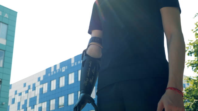 Ein-Mann-mit-einem-modernen-bionische-Armprothese-steht-in-der-Stadt.-Zukunftskonzept.