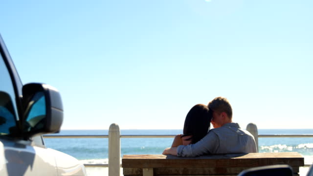 Rear-view-of-couple-sitting-on-bench-near-railings-4k