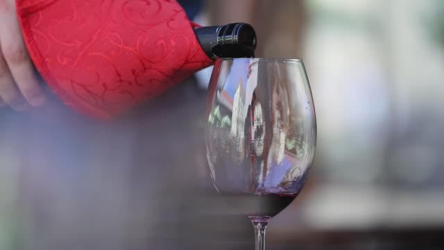Rotwein.-Kellner-gießt-Wein-im-Glas-im-Restaurant-Closeup