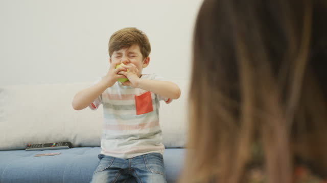 Junge-isst-einen-Apfel-im-Wohnzimmer