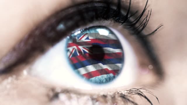 Mujer-ojo-azul-en-primer-plano-con-la-bandera-del-estado-de-Hawa-en-el-iris,-estados-unidos-de-América-con-movimiento-de-viento.-concepto-de-vídeo