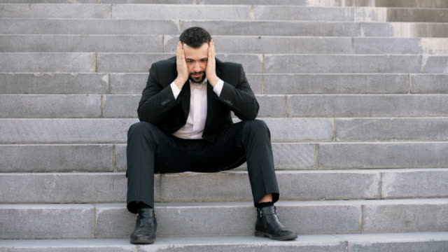 Un-joven-empresario-molesto-con-estrés-y-sentado-en-las-escaleras-de-la-calle.-Empresario-que-tiene-el-concepto-de-problemas-de-trato