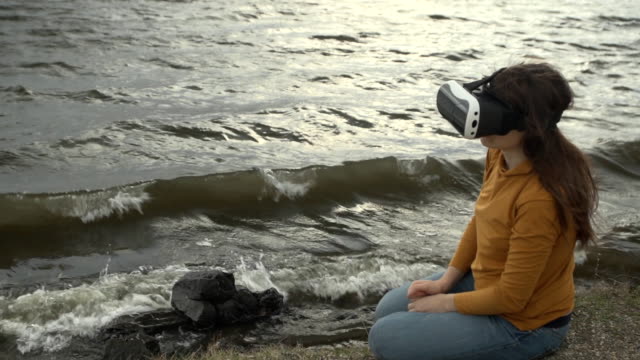 A-young-woman-uses-virtual-reality-glasses-next-to-strong-waves.