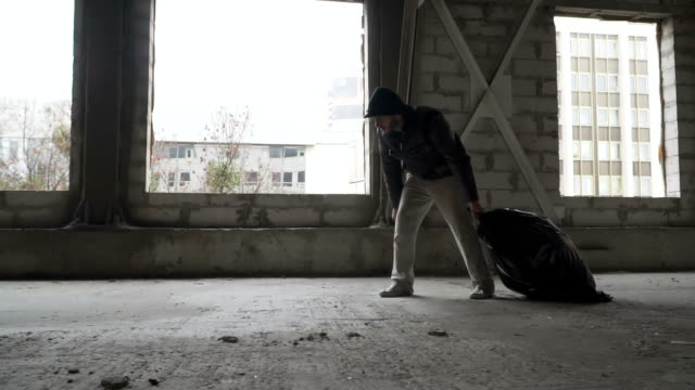 Schmutzige-Obdachlosen-zieht-einen-Müllsack-in-verlassenen-Gebäude