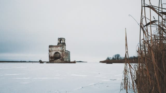 Verlassene-Kirchengebäude-in-der-Mitte-des-zugefrorenen-See-mit-Schnee-bedeckt