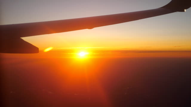 View-from-airplane-window-to-beautiful-sunrise-or-sunset.-Wing-of-plane-and-cloud-in-sky.-Concept-of-travel-or-tourism.-Close-up-Side-view