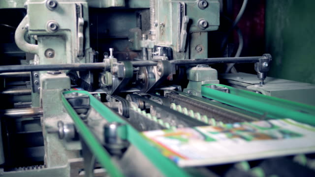 An-industrial-machine-is-cutting-off-edges-of-printed-magazines