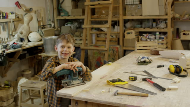 Muchacho-sonriente-posando-en-el-taller-de-carpintería