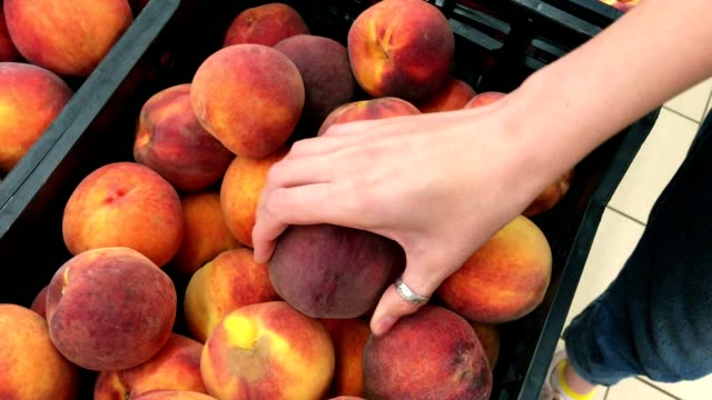 Caucasian-woman-picking-peaches-in-the-supermarket