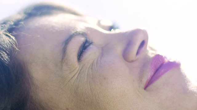 Woman-close-up-looking-up-at-sky-dreaming,-lying-dreamer,-smiling-female-enjoys