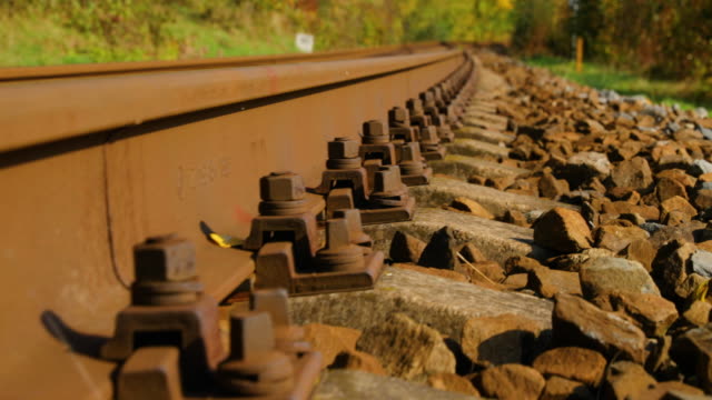 Slow-Close-up-view-of-security-bolts-at-train-tracks-in-slow-camera-movement-forward-outside-the-city-during-a-sunny-day-in-autumn.