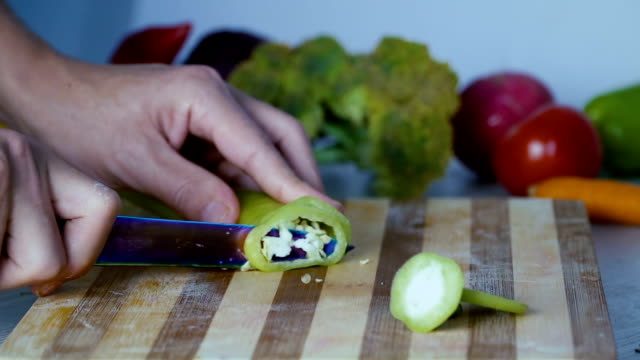 Chef-is-cutting-vegetables-in-the-kitchen,-slicing-sweet-green-bell-pepper.-Close-up-footage