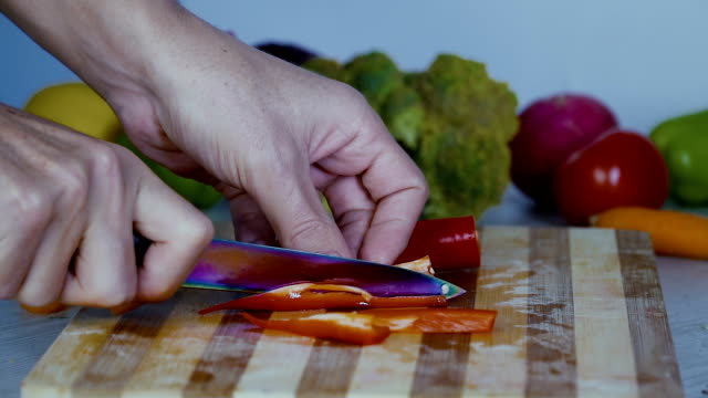 Chef-is-cutting-vegetables-in-the-kitchen,-slicing-sweet-red-bell-pepper